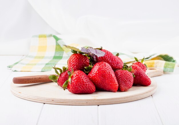 Side view fresh strawberry and basil on a board