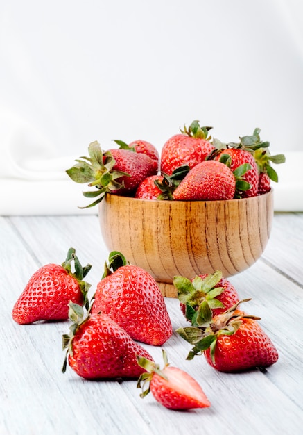 Side view fresh strawberry in a bowl on white wooden background