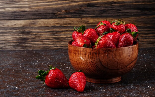 Side view fresh strawberry in bowl on wooden background