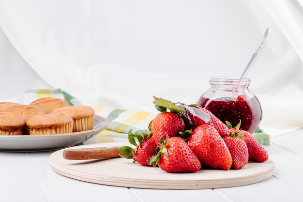 Side view fresh strawberry cupcakes and strawberry jam on white background