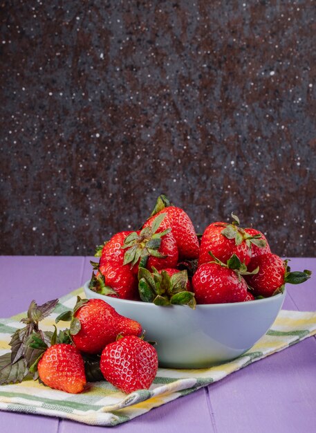 Side view fresh strawberry with basil on purple and black background