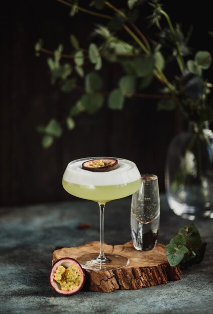 Side view of fresh tropical cocktail with passion fruit on a wooden stand