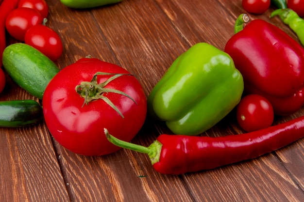 Side view of fresh vegetables ripe tomatoes cucumbers red chili pepper and colorful bell peppers on wood rustic