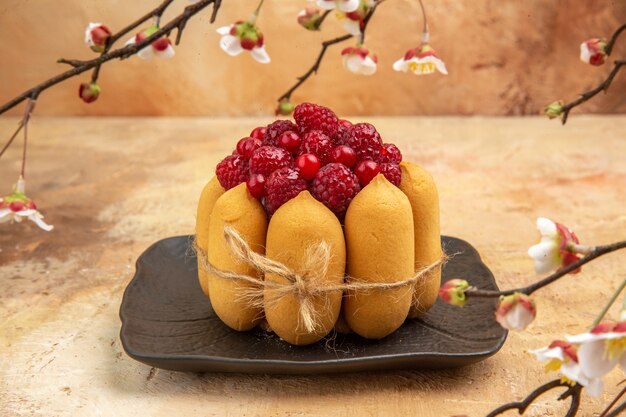 Vista laterale della torta regalo appena sfornata con frutta sulla tavola di colori misti