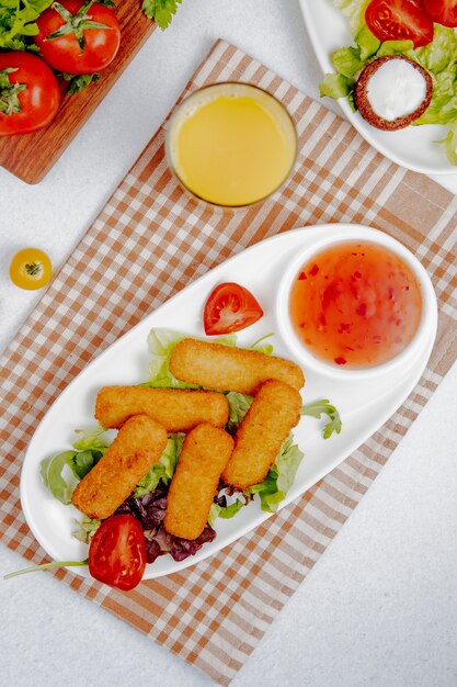 Side view of fried cheese sticks with sauce on the table