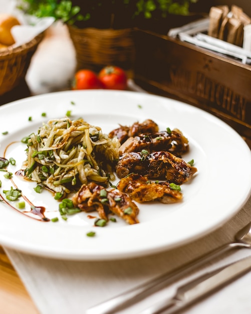 Side view fried meat in sauce with cabbage and green onions