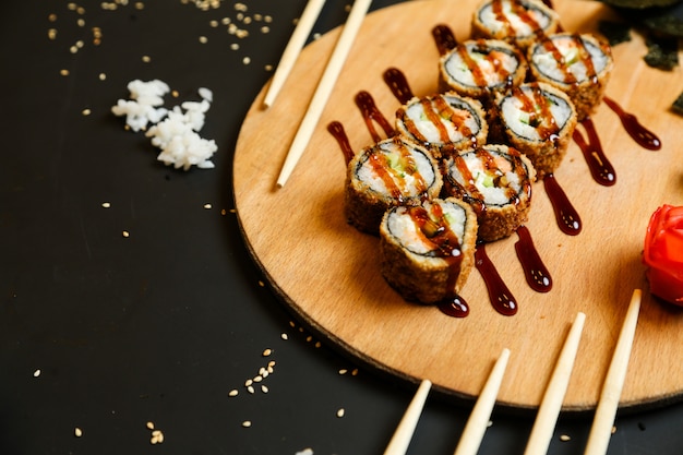 Side view fried rolls with sauce on a stand with wasabi