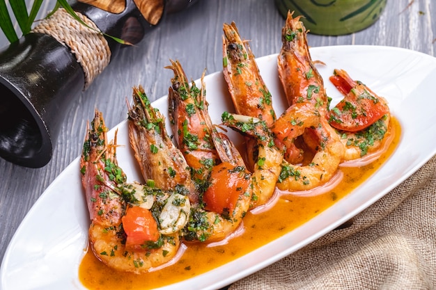 Free photo side view fried shrimps in sauce with tomatoes and herbs