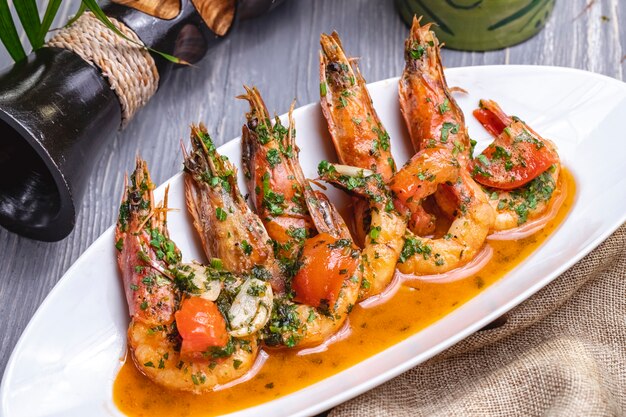 Side view fried shrimps in sauce with tomatoes and herbs