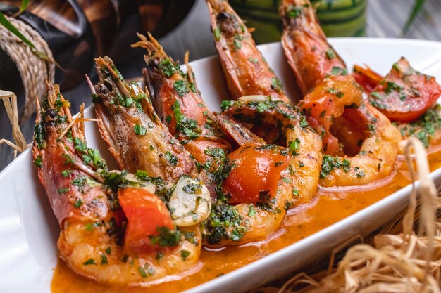 Side view fried shrimps in sauce with tomatoes and herbs