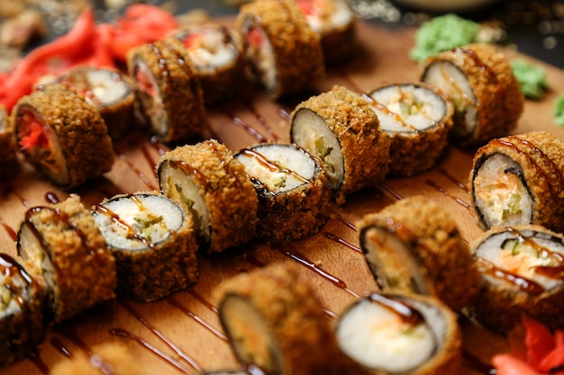 Side view fried sushi rolls on a tray with ginger and wasabi