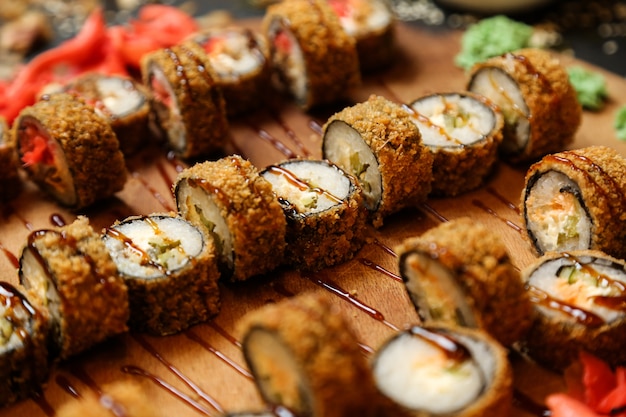 Жареные суши-роллы на подносе с имбирем и васаби, вид сбоку