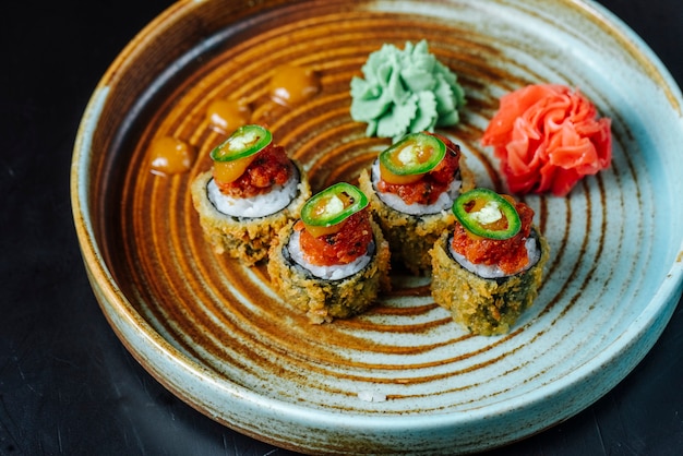 Side view fried sushi rolls with wasabi and ginger on a plate