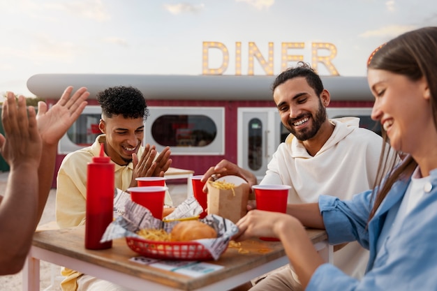 Foto gratuita amici di vista laterale che mangiano all'aperto