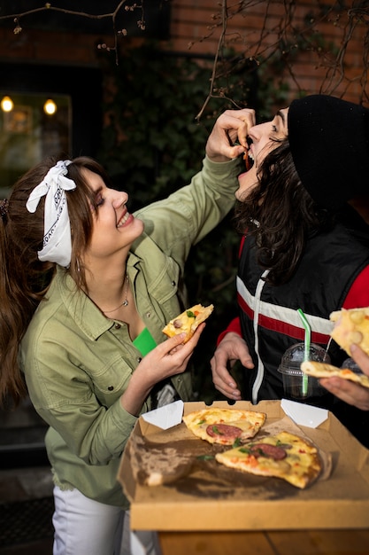 Free photo side view friends eating pizza