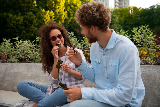 Free photo side view friends eating seaweed snacks