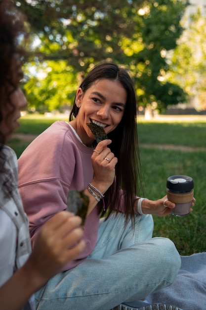 Free photo side view friends eating seaweed snacks