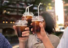 Free photo side view friends holding iced coffee