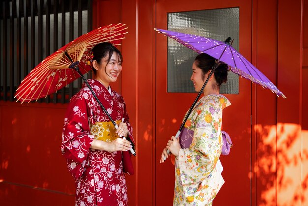 Side view friends holding wagasa umbrellas