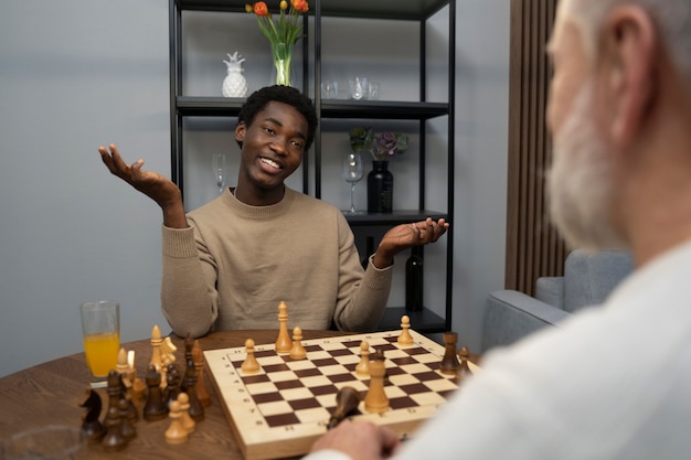 Free photo side view friends playing chess indoors