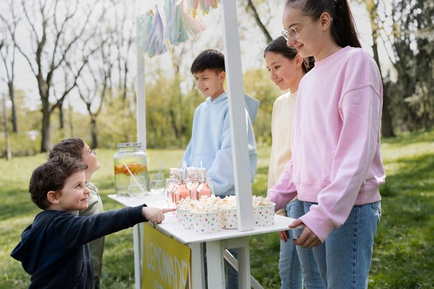 Side view friends selling lemonade