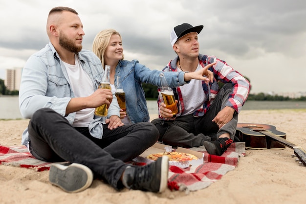 Side view friends sitting on a beach