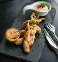 Free photo side view frog legs in batter with a slice of lemon and sauce