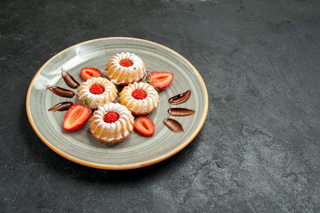 Вид сбоку аппетитное печенье печенье с шоколадом и клубникой в тарелке с левой стороны стола