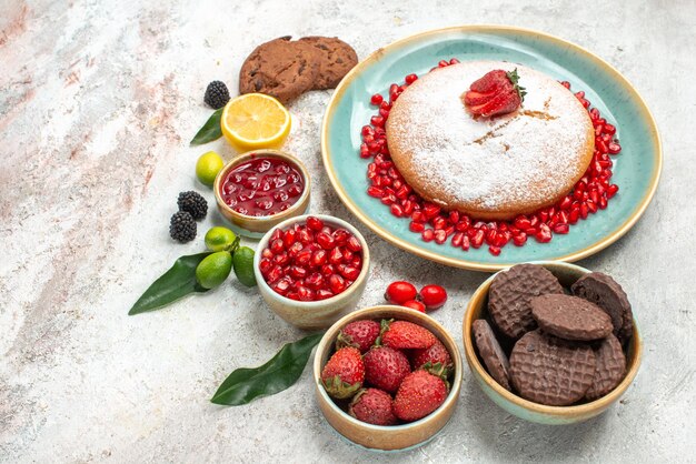 Side view from afar berries and cookies lemon jam cookies the cake with strawberries citrus fruits