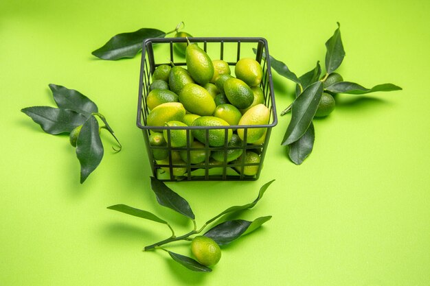 Side view from afar citrus fruits basket with citrus fruits green leaves on the green table