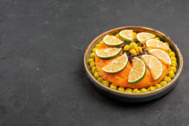 Side view from afar citrus fruits and chocolate cake with chocolate and citrus fruits on the right side of the black table