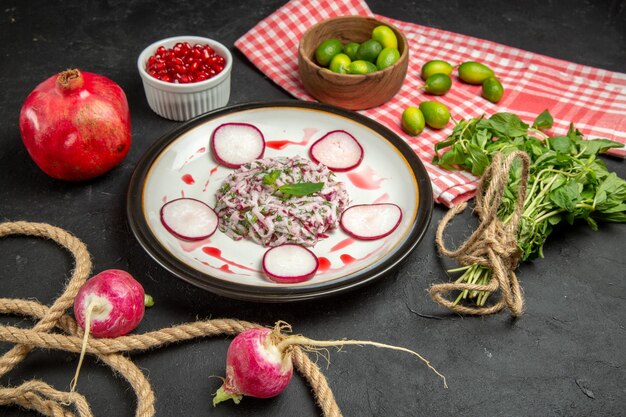 Side view from afar a dish a dish of redish greens rope pomegranate citrus fruits