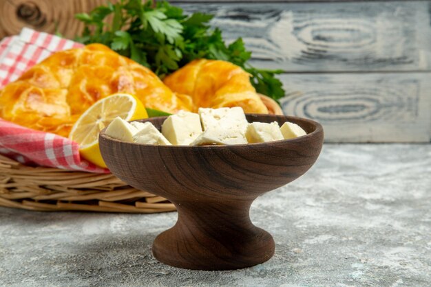 遠くのパイとチーズのレモンプレートとパイハーブレモンとライムと木製の背景のバスケットのテーブルクロスからの側面図