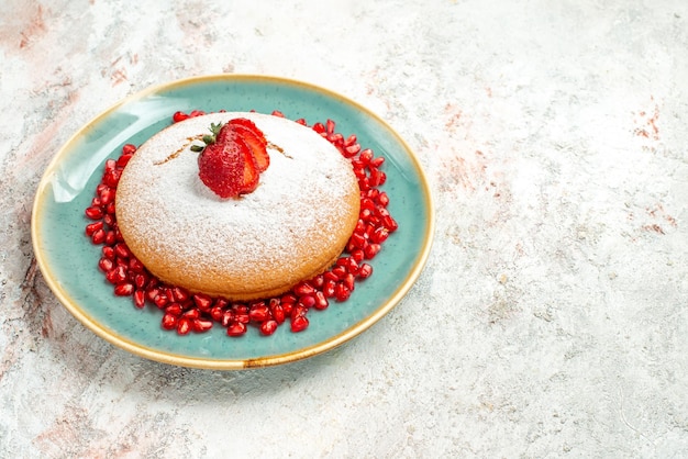 Side view from afar strawberry pomegranate the appetizing cake with strawberries and pomegranate on the blue plate