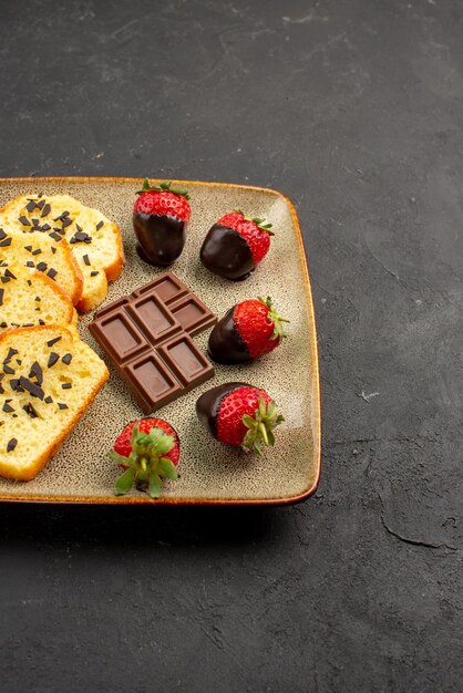 Side view fron afar strawberries and chocolate cake with appetizing chocolate chocolate-covered red strawberries on plate on the left