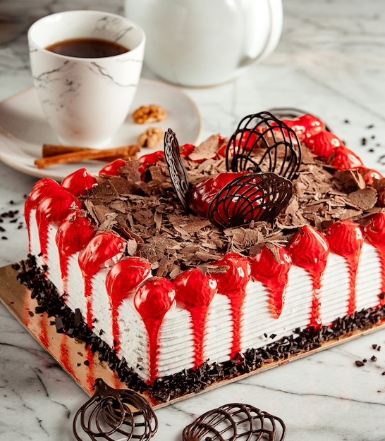 Vista laterale della torta di frutta condita con scaglie di cioccolato sul tavolo servito con tè