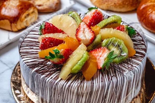 Side view fruit cake with vanilla cream chocolate kiwi orange pineapple and strawberry