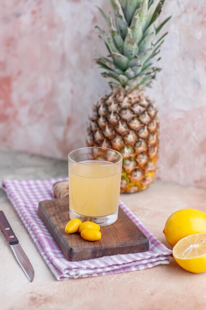 Side view of fruit juice and kumquats on wooden cutting board on purple stripped towel whole cut lemons and grapefruit on pastel colors background