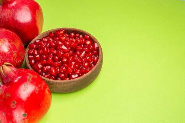 Вид сбоку плоды аппетитных семян граната в миске три спелых красных граната