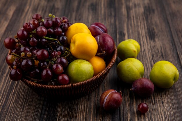 ネクタコットがバスケットと木製の背景にブドウをプルオットするときの果物の側面図