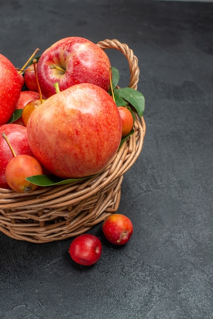 Вид сбоку фрукты красно-желтые вишни и яблоки в корзине