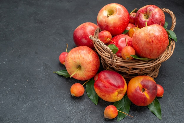 Side view fruits the wooden basket with fruits and berries with leaves