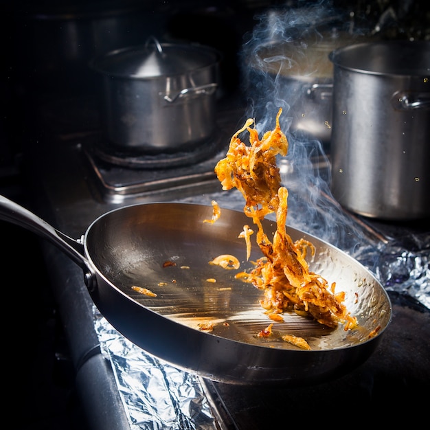 Side view frying onions with pan in stove2