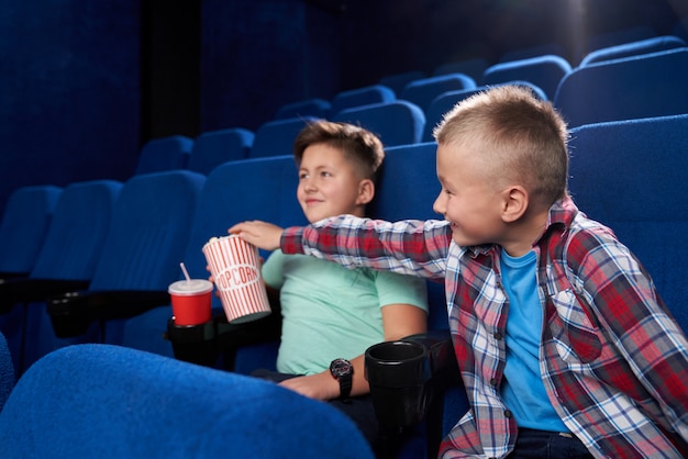 Vista laterale dei ragazzi divertenti che guardano insieme film comico nel cinema
