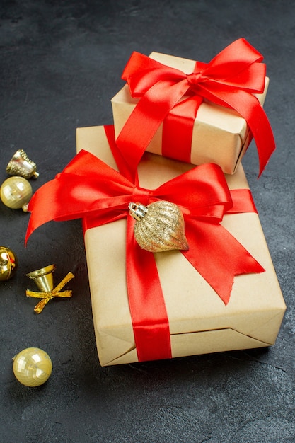 Free photo side view of gift box with red ribbon and decoration accessories on dark background