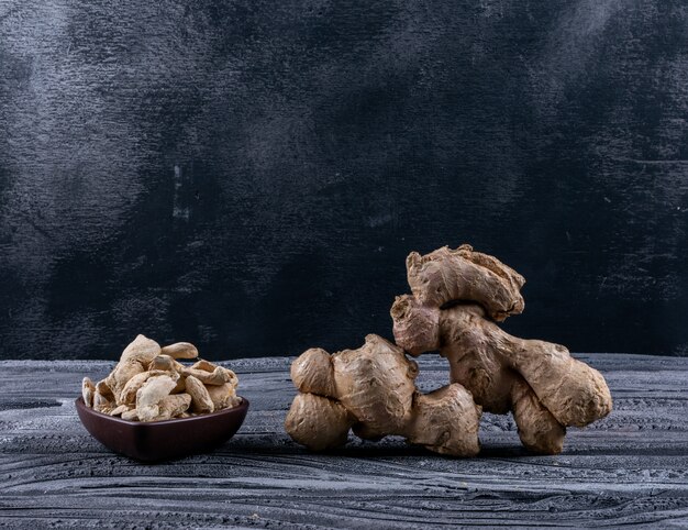 Side view ginger in heart shaped bowl on dark wooden background. horizontal space for text