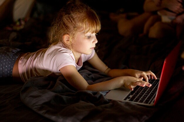 Вид сбоку девушка в постели с ноутбуком