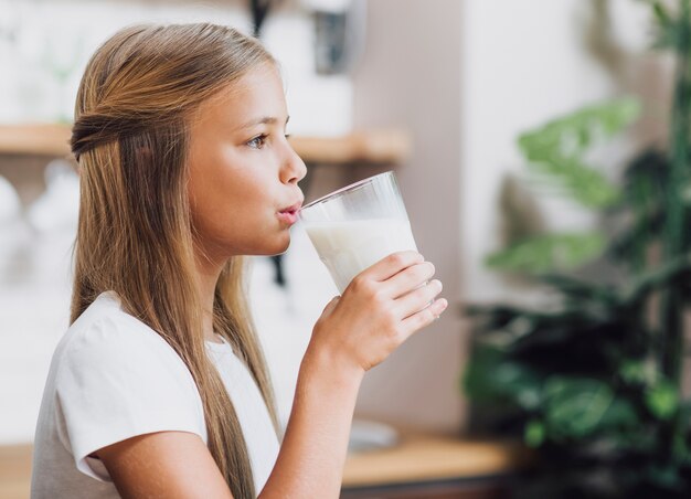 Боковой вид девушка пьет стакан молока