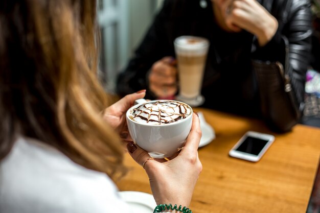 Side view a girl drinks cappuccino