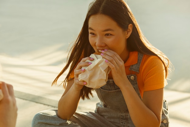 Foto gratuita ragazza di vista laterale che mangia hamburger